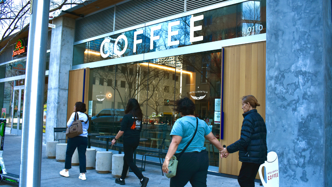 A group of people walk in front of Intelligentsia Coffee